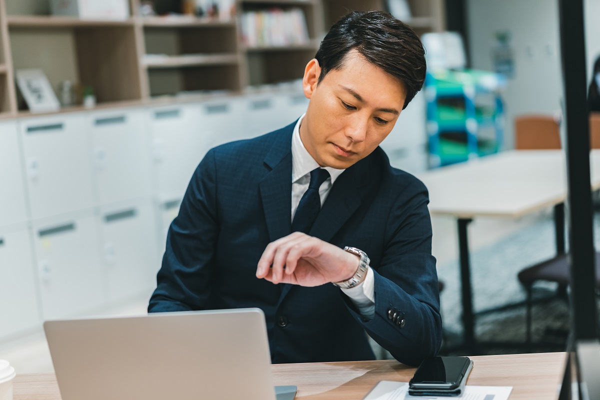残業時間の問題を解決！長時間労働の原因を知って対策しよう（腕時計を見つめるビジネスパーソン）